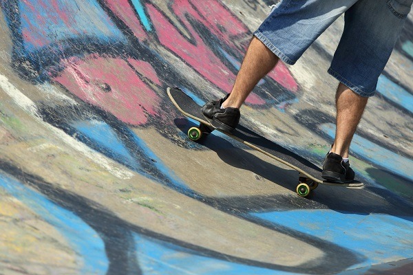 Boy legs on a skateboard in a half pipe with graffiti