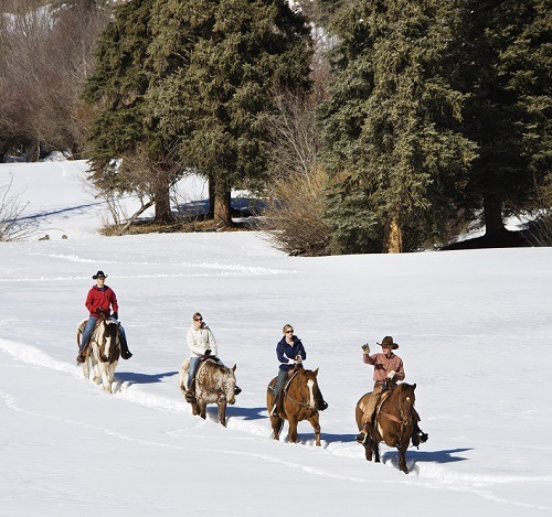 Group horseback riding in snow.